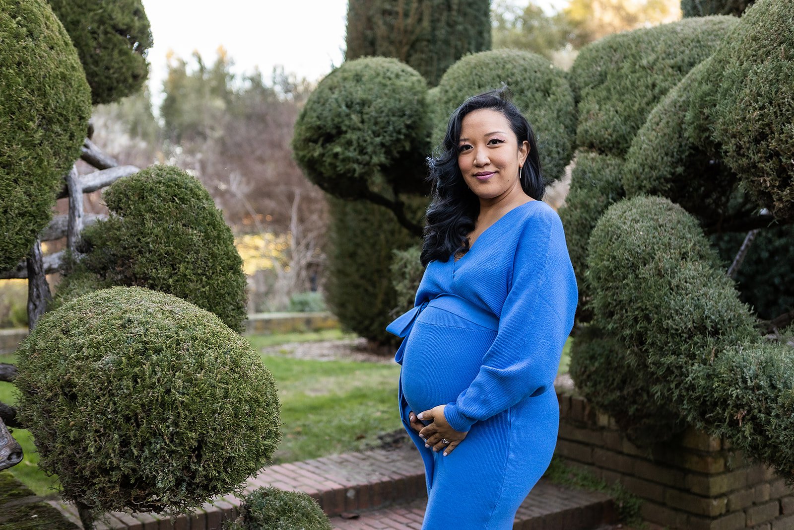 Radiant expectant mother in a vibrant blue dress posing at the lush Filoli Gardens, a picture-perfect moment of anticipation.