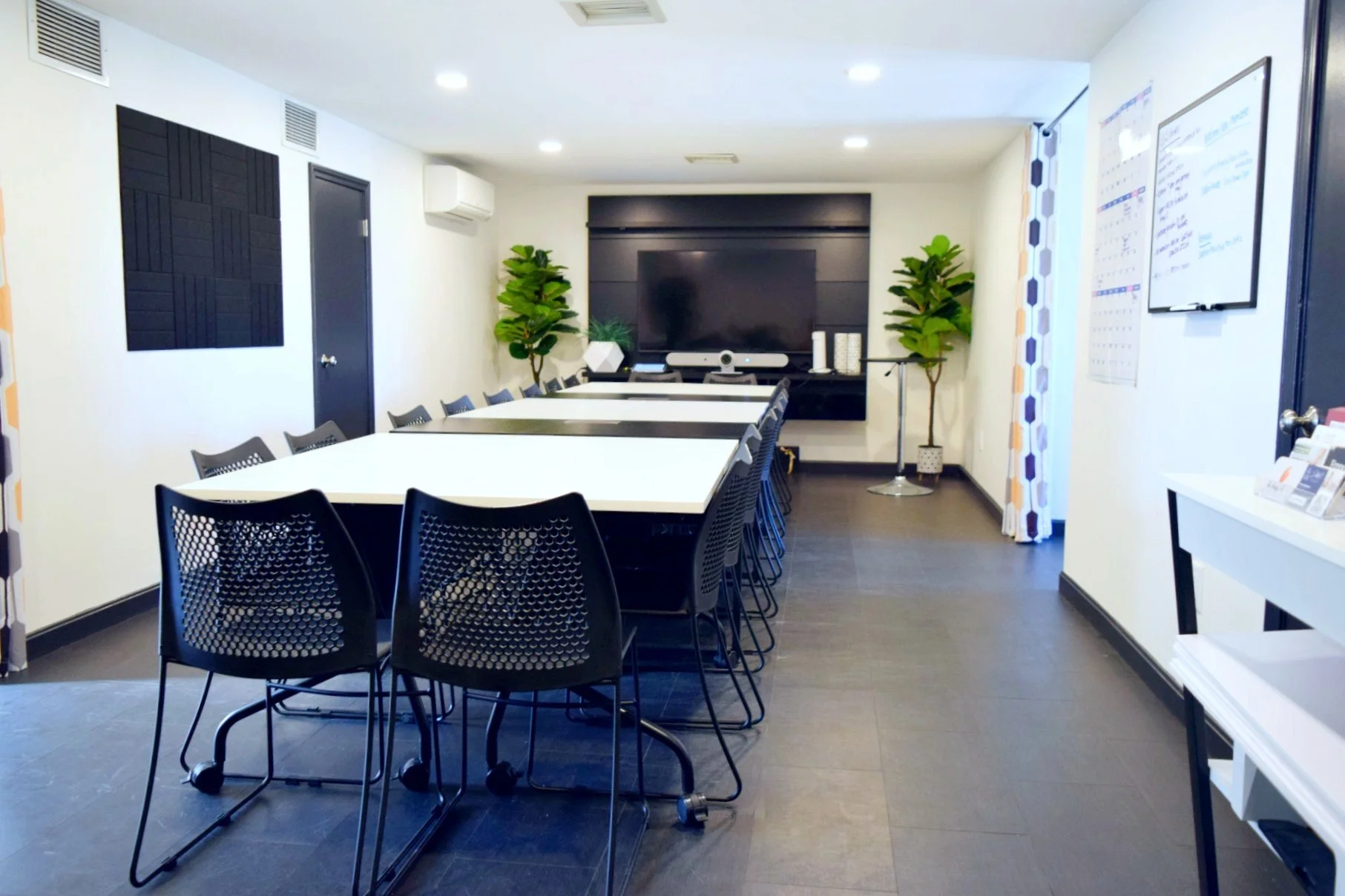 Interior of a modern room with a long conference room table, large screen tv for virtual conferencing. 