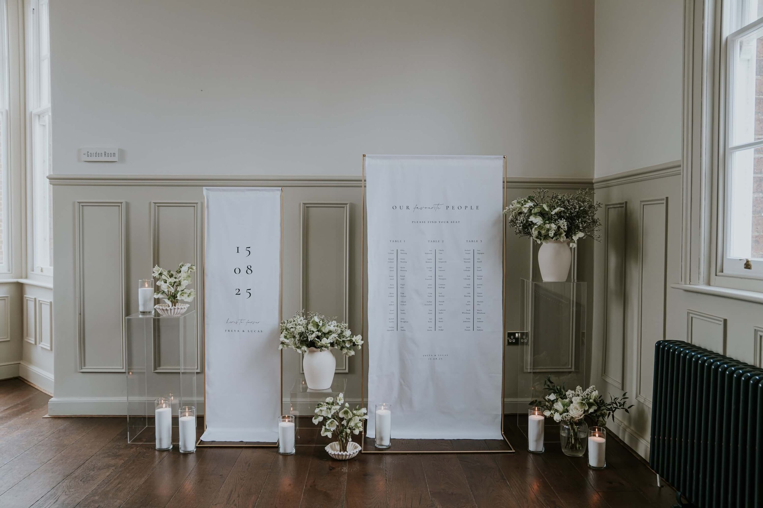 white fabric signage styled with cylinder vases and fresh florals in a wood panelled room
