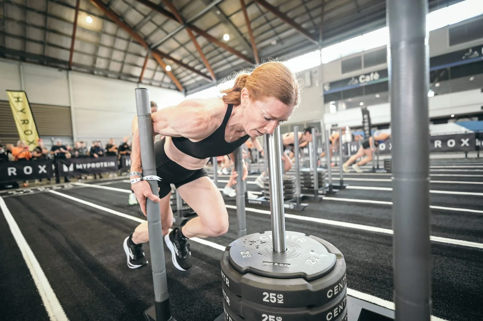 Alana McDonald pushing a sled at a HYROX race after training with Urban Fitness Wellington