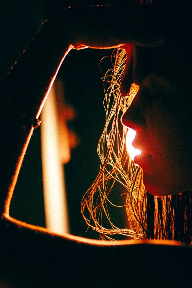 A person wearing a welding helmet is shown in profile with their face illuminated by the bright sparks from welding.