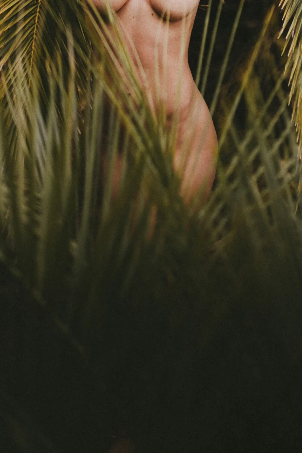 Partially visible face of a person surrounded by tall grass or plants.