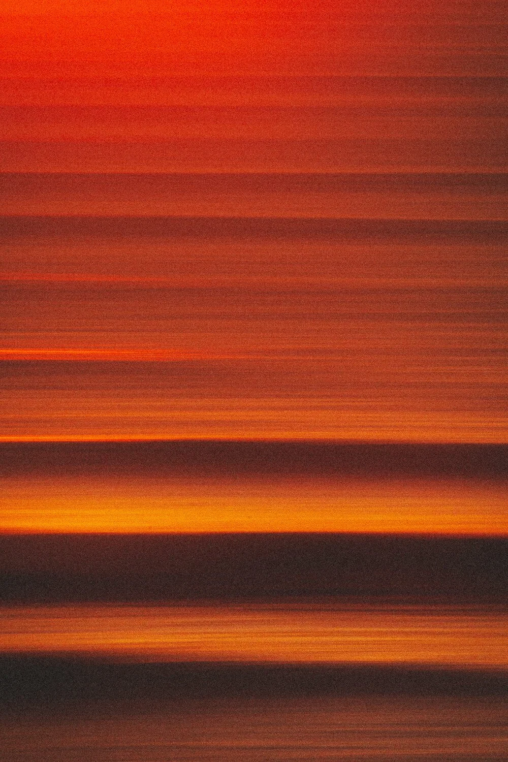 Blurred sunset with horizontal streaks of orange, red, and yellow colors.