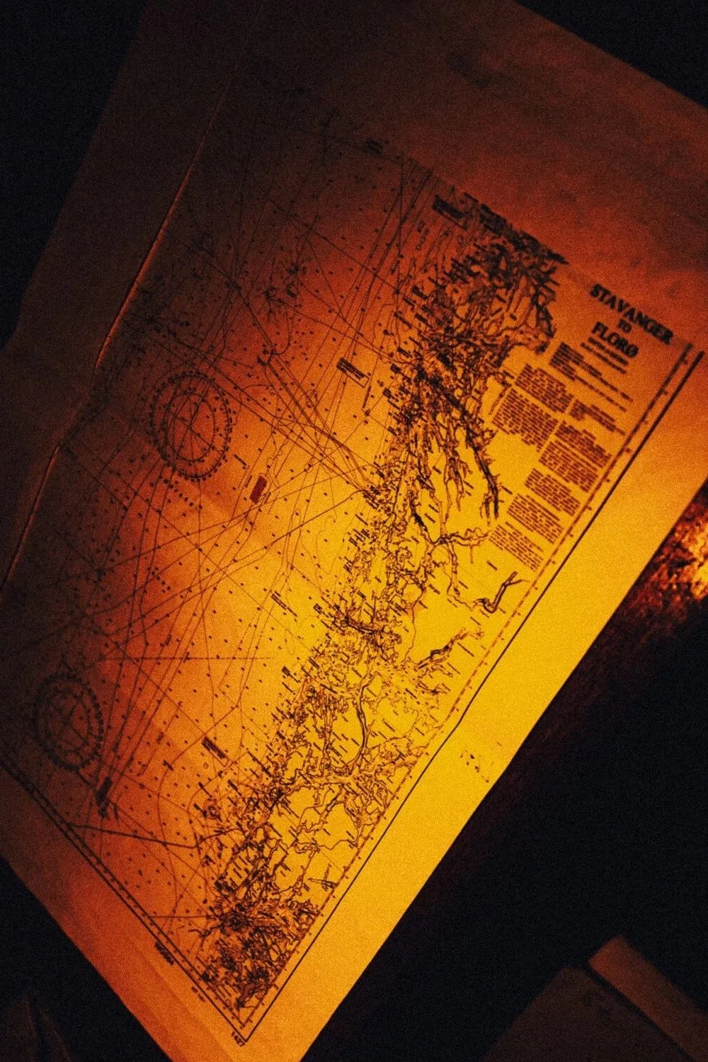 Carte topographique ou navale éclairée par une lumière chaude, avec des lignes et des textes en anglais illustrant des zones géographiques.