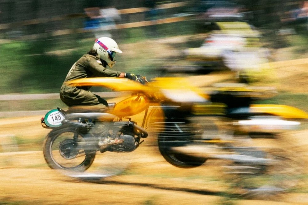 Course de motocross avec deux motards portant des casques sur une piste en terre, mouvement flou.
