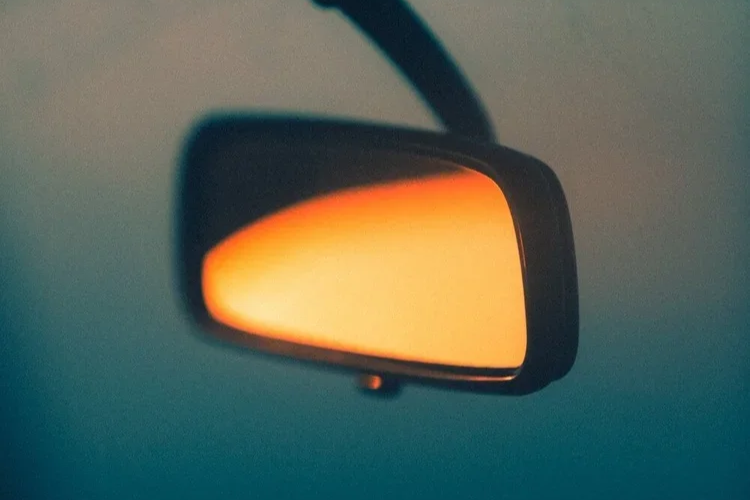 Rétroviseur de voiture avec reflet orange, suspendu à l'intérieur du véhicule.