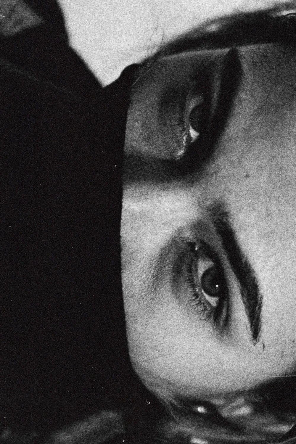 Portrait en noir et blanc d'une femme avec un maquillage marqué autour des yeux, regardant vers la caméra, avec une expression intense.