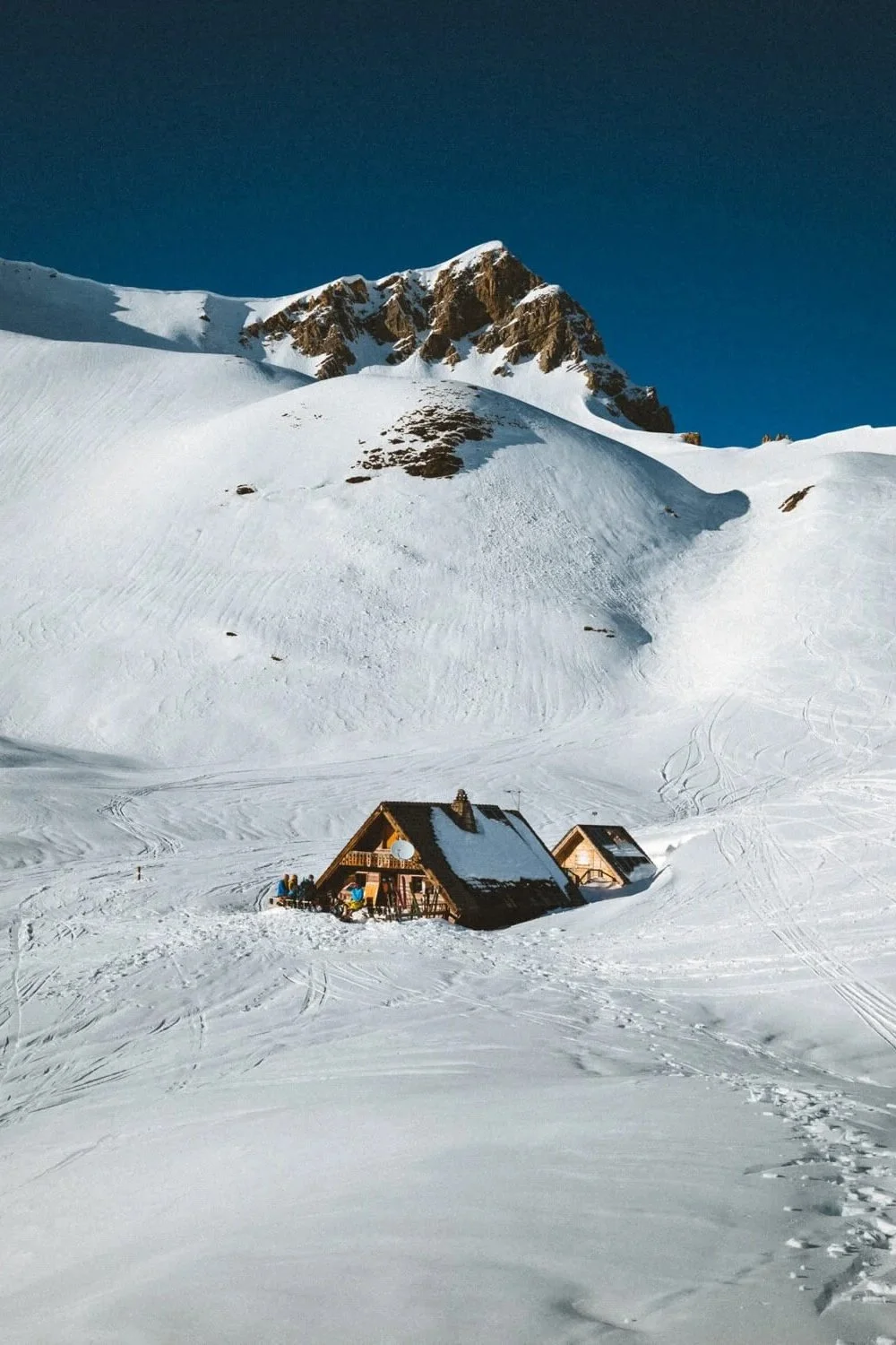 Paysage de montagne enneigée avec chalets et ciel bleu.
