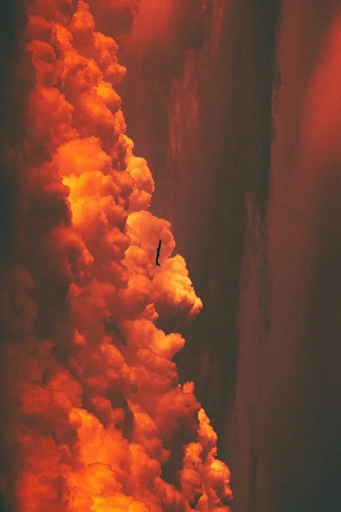 A sky filled with thick, orange and red clouds during either a sunset or wildfire.