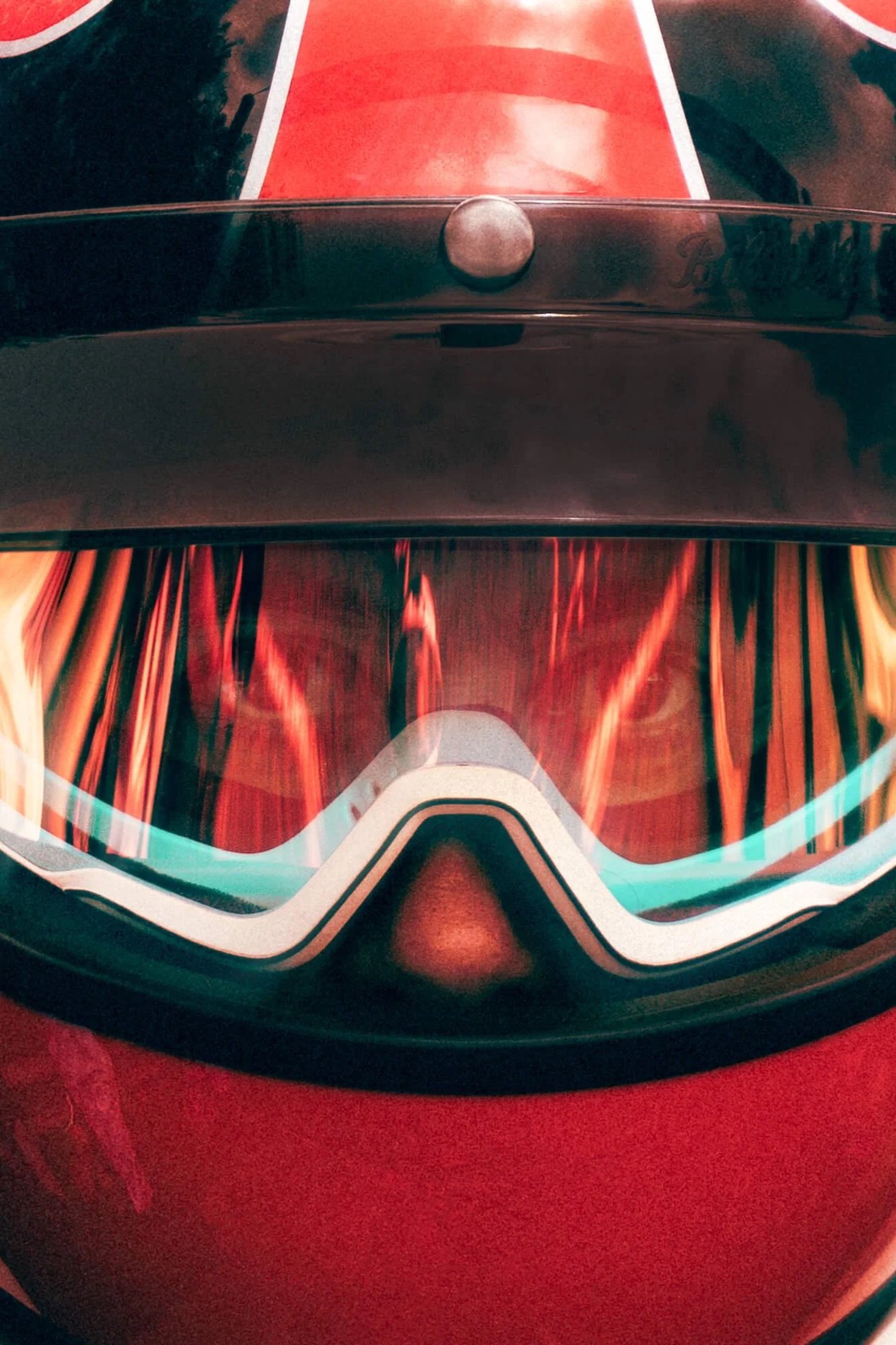 Close-up of a red and black motorcycle helmet with a tinted visor and a reflection of trees on the visor.