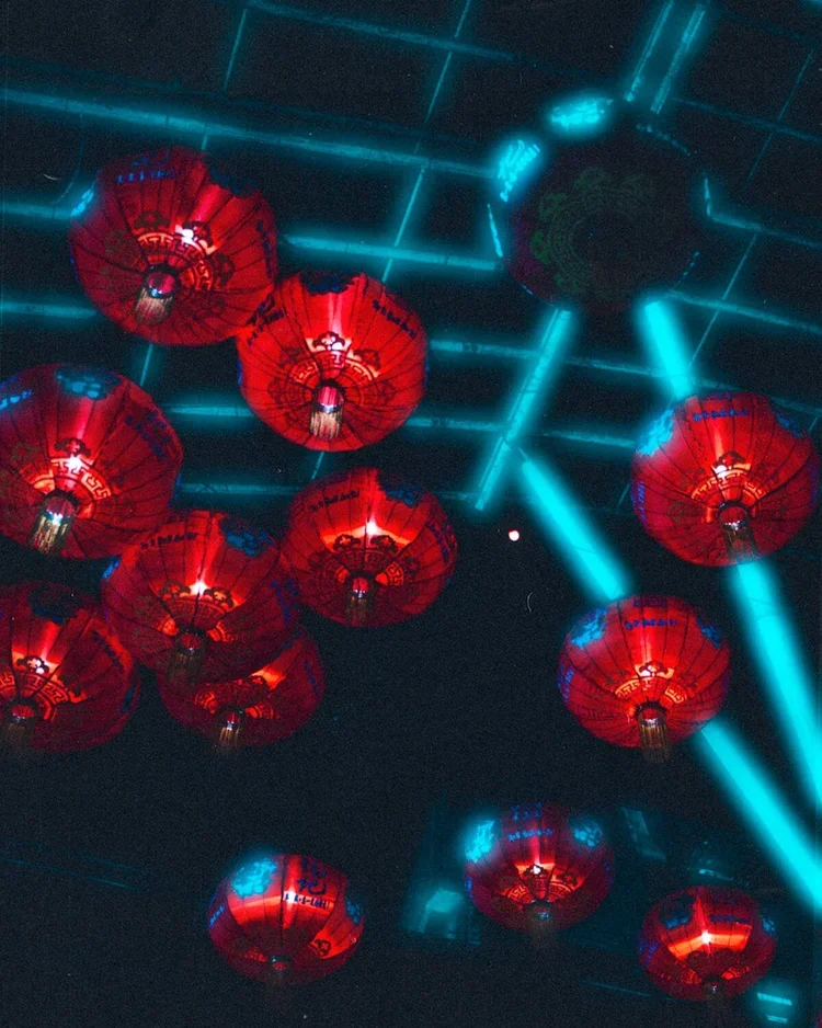 L'image montre plusieurs lanternes rouges chinoises suspendues au plafond avec des lignes lumineuses bleues formant une structure géométrique comme un plafond moderne ou un décor lumineux.