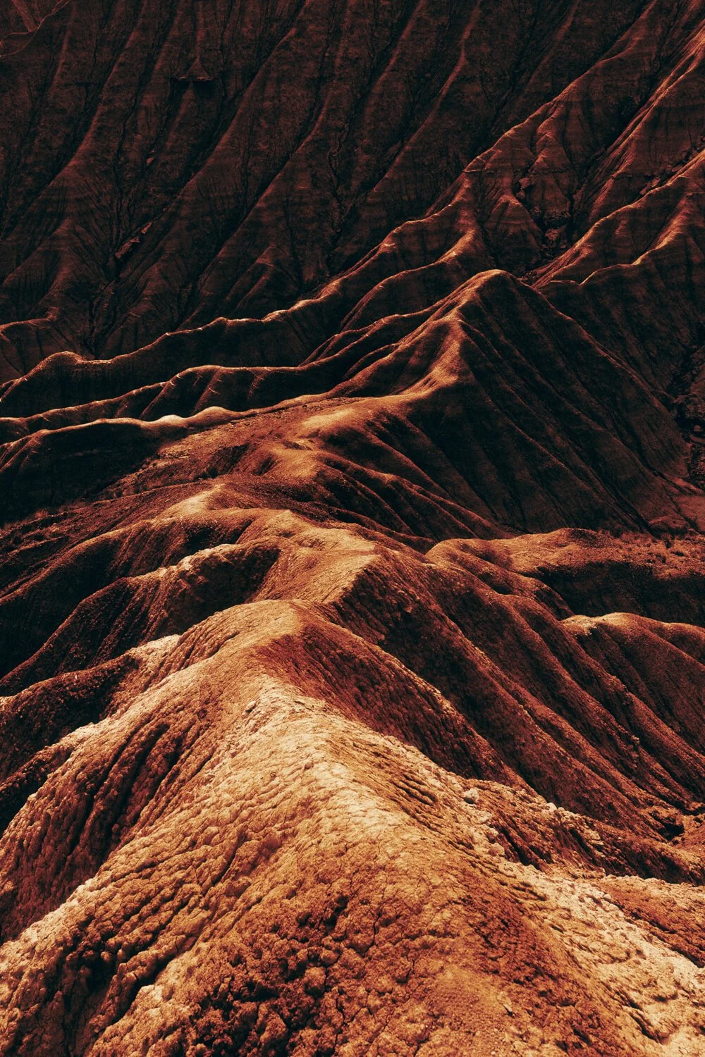 Paysage de montagnes aux couleurs rouges et brunes avec des crêtes escarpées et des formations rocheuses accidentées.