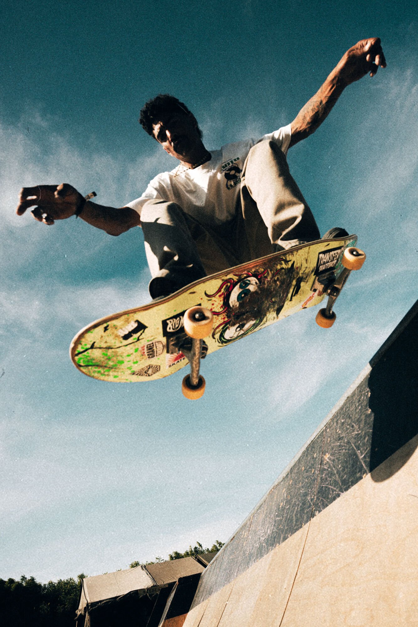 Skateboarder performing a trick on a skateboard at a skatepark during the day.