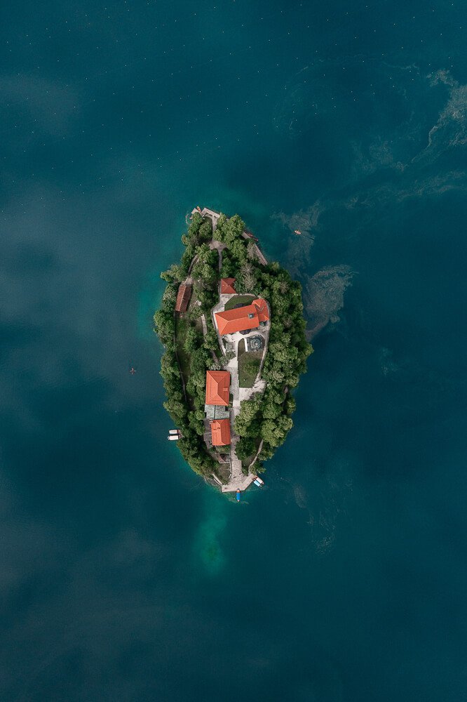 An aerial view of a small island with several buildings surrounded by blue water.