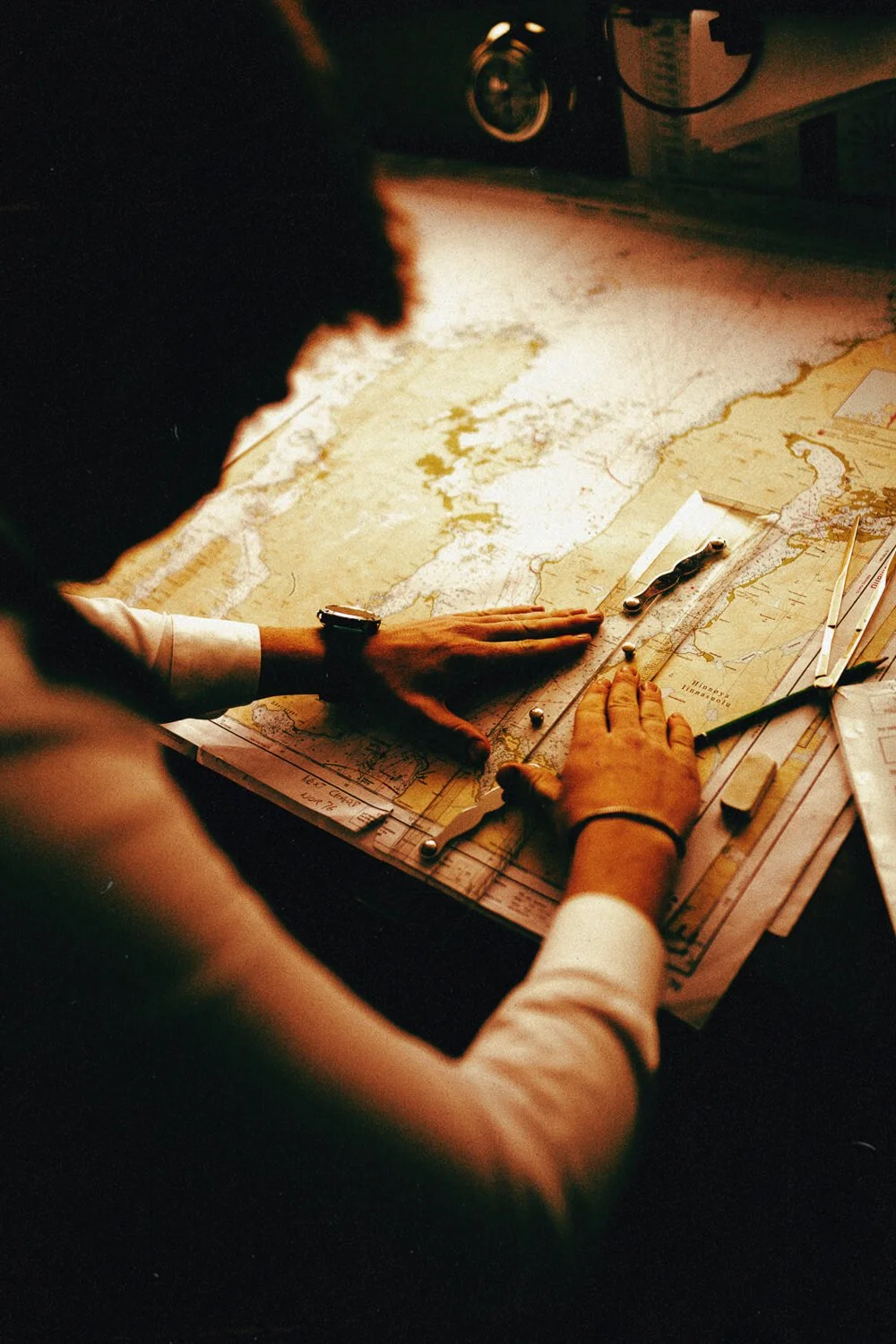 Personne utilisant une règle pour mesurer une carte géographique sur une table.