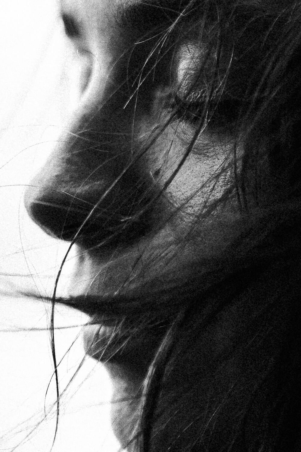 Close-up side profile of a woman with wet hair covering part of her face, captured in black and white.