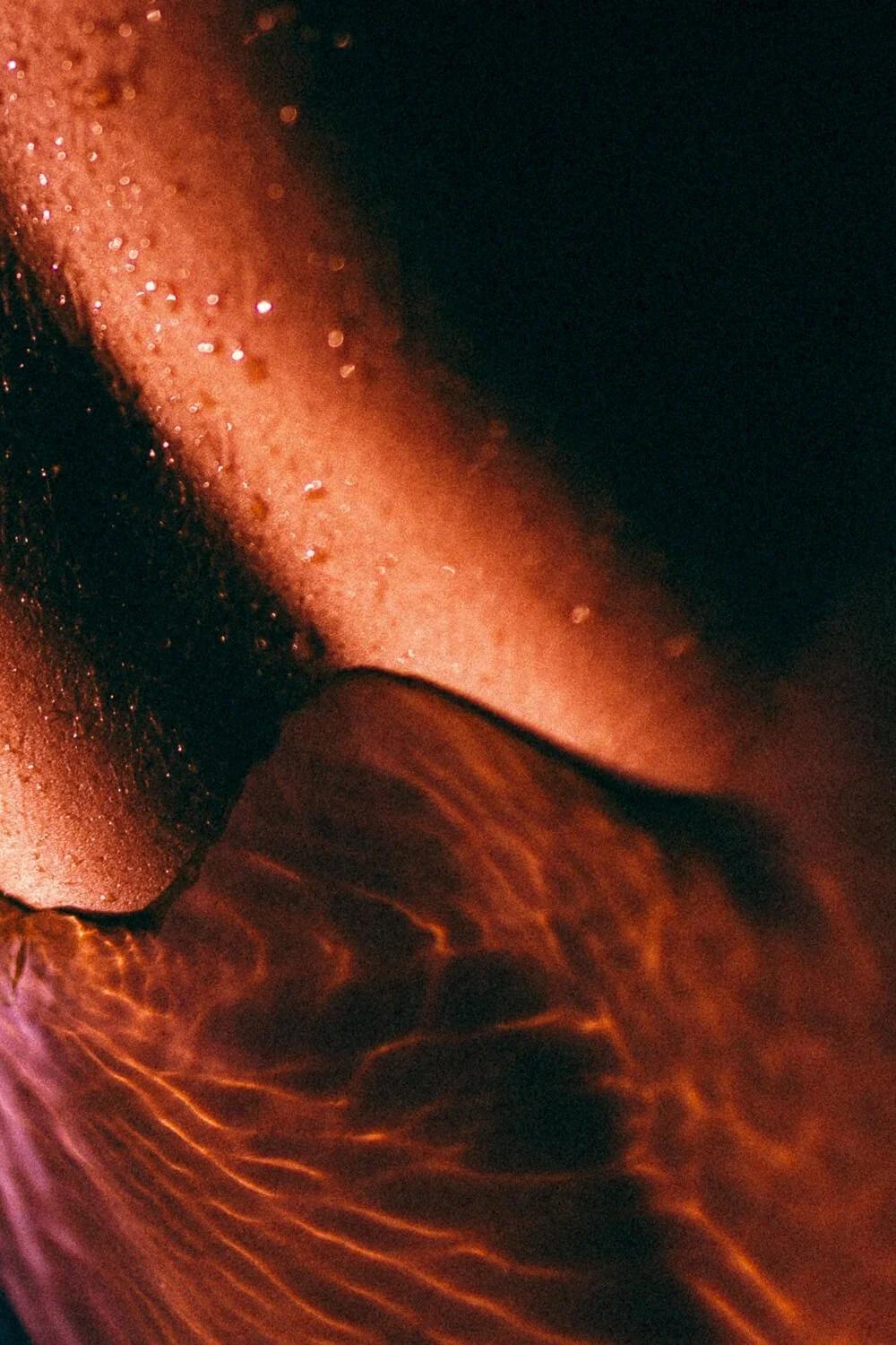 Gros plan de la surface d'une langue humide et brillante, avec des papilles et une texture rugueuse, éclairée en rouge et orange.