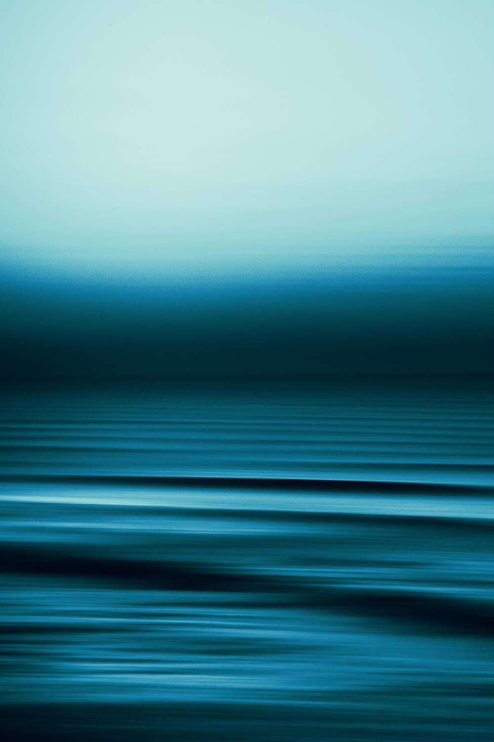 Abstract blurred landscape with shades of blue and teal, resembling water and sky.