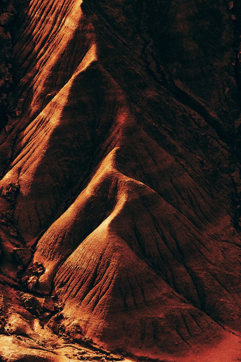 Photo de formations rocheuses rougeâtres avec des sommets pointus et des crevasses profondes, en terrain désertique.