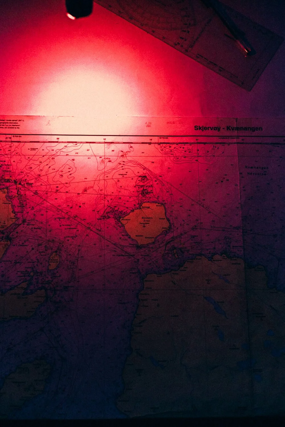 Carte maritime de l'île de Kvaløy, avec un éclairage rouge lumineux et une règle à proximité.