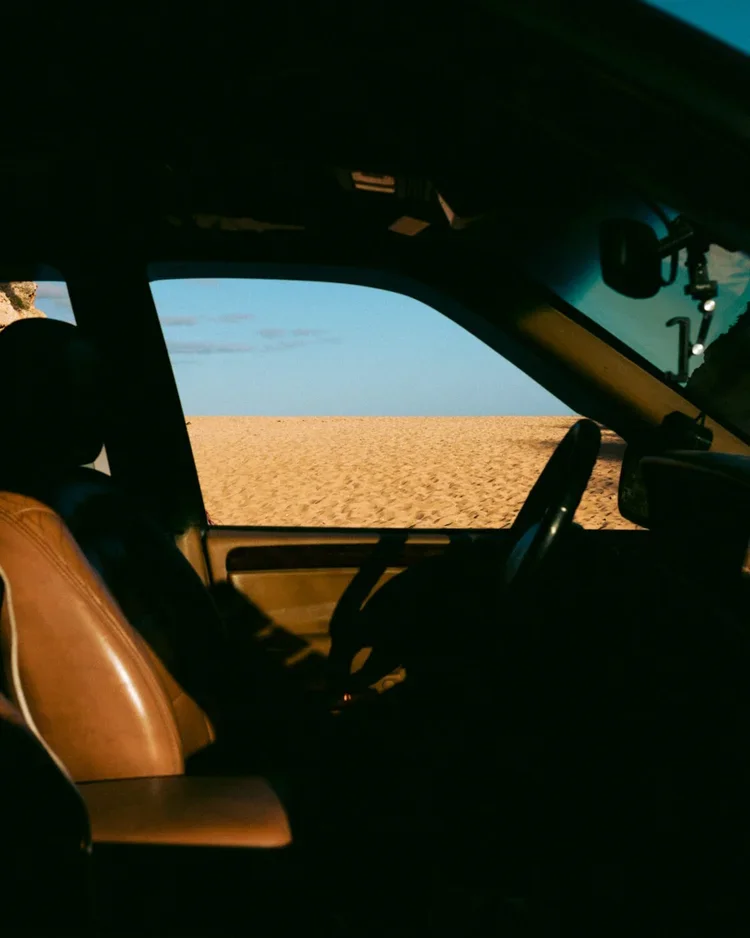Intérieur d'une voiture avec vue sur une zone sablonneuse ou désertique à travers la fenêtre
