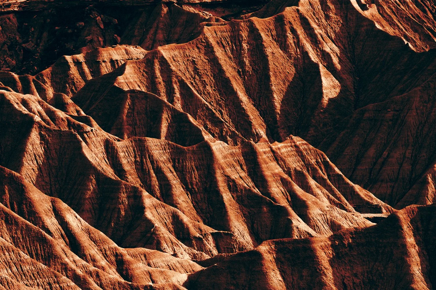 Montagnes colorées avec des formations rocheuses rouges et brunes, ambiance de canyon aride, lumière naturelle.