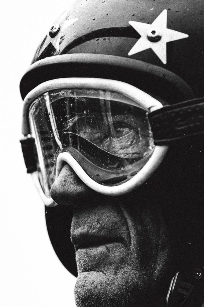 Close-up of a person wearing vintage goggles and a helmet with a star insignia, black and white photo.