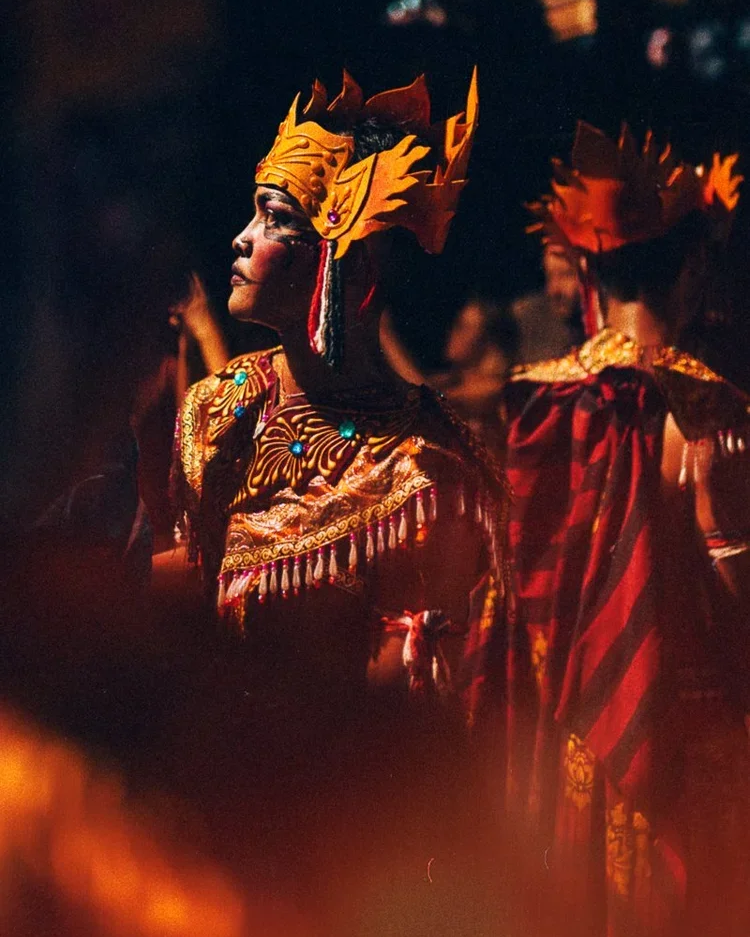 Des personnes en costumes traditionnels colorés, portant des coiffes élaborées lors d'une procession ou d'une célébration culturelle.