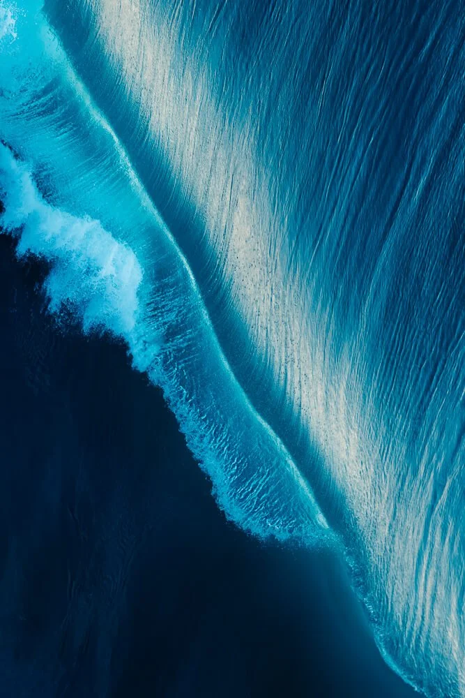 An aerial view of ocean waves breaking, showcasing the water's movement and texture.