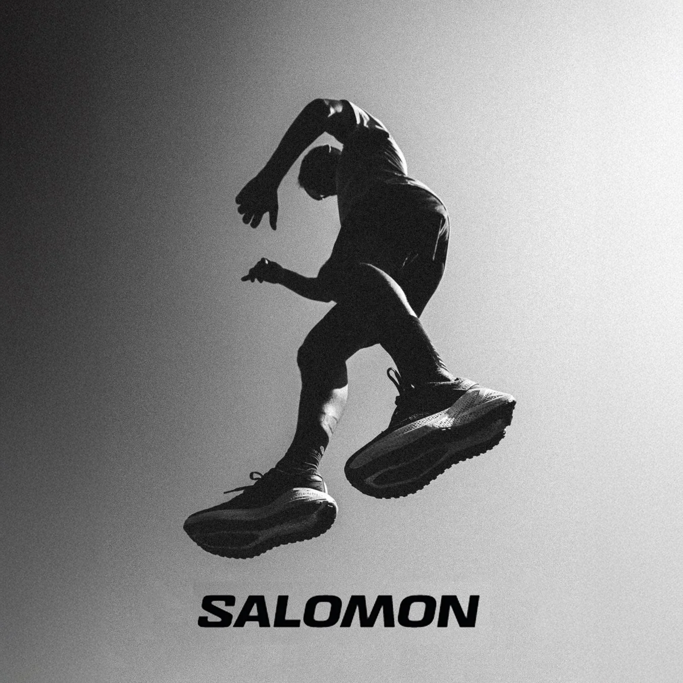 Silhouette d'un homme en saut avec les bras levés, portant des chaussures de sport, contre un fond gris dégradé. Le mot "Salomon" est écrit en dessous.