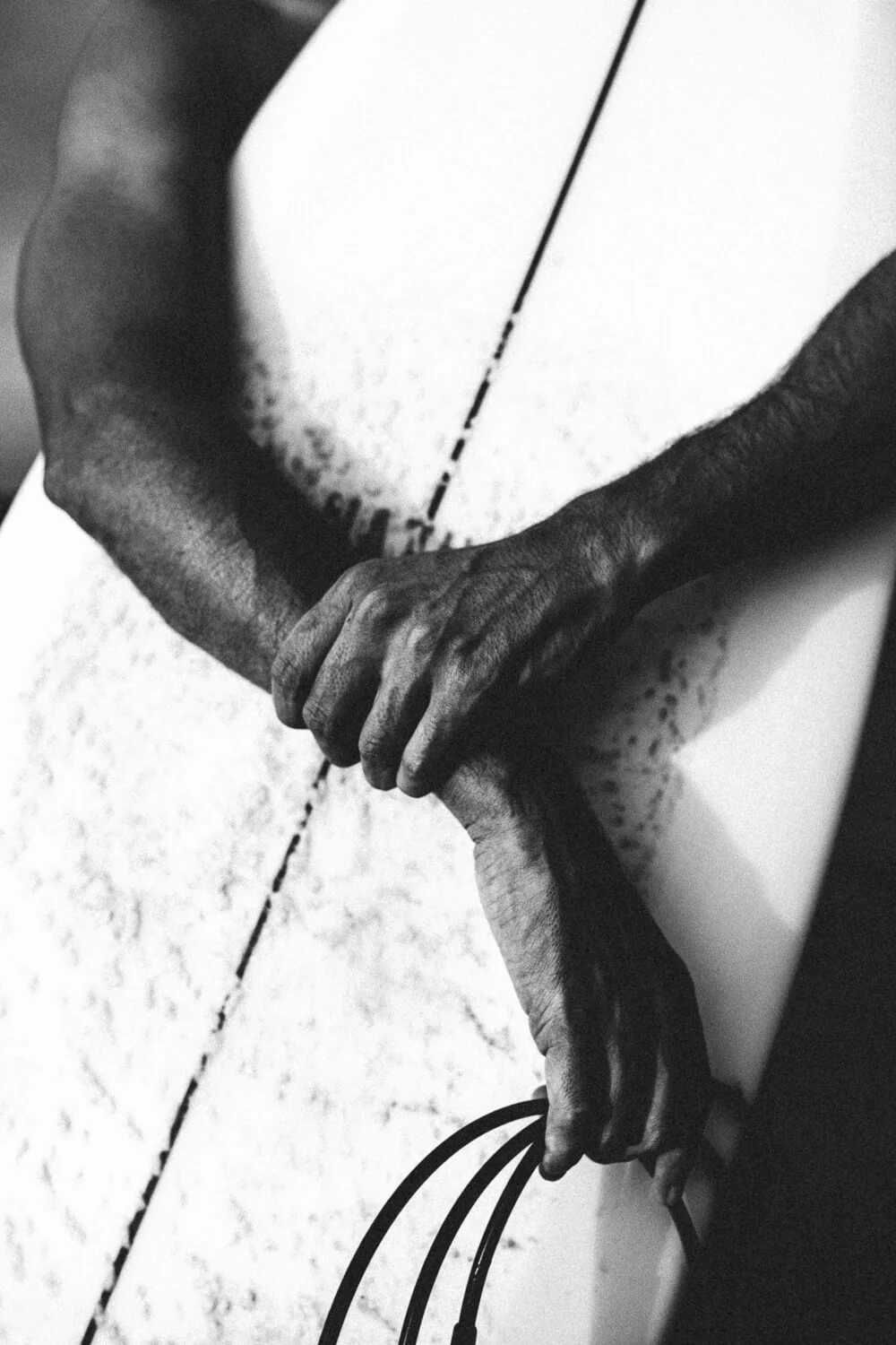 Une main noire s'appuie sur une surface blanche, tenant des câbles ou des fils.