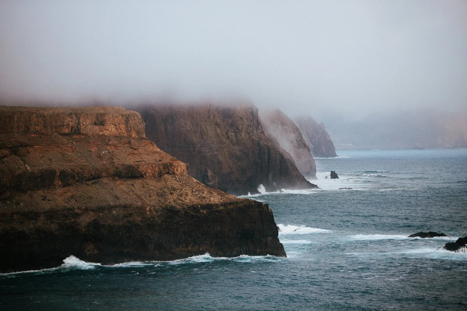 Cliffs along a stormy ocean under foggy sky