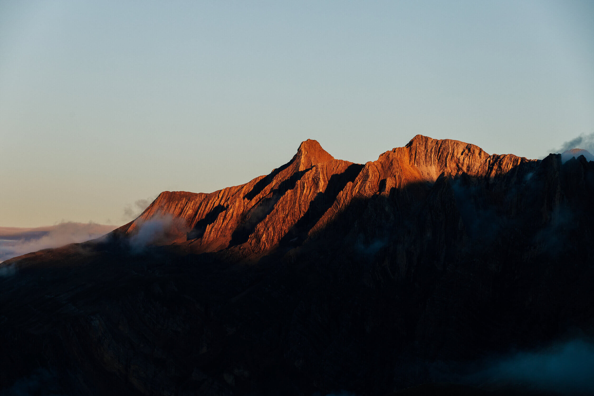Chaîne de montagnes au coucher du soleil avec des ombres profondes et un léger brouillard.