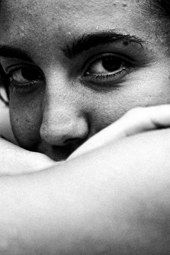 Close-up of a person's face, focusing on the eyes and nose, with the person partially resting their face on a soft surface.