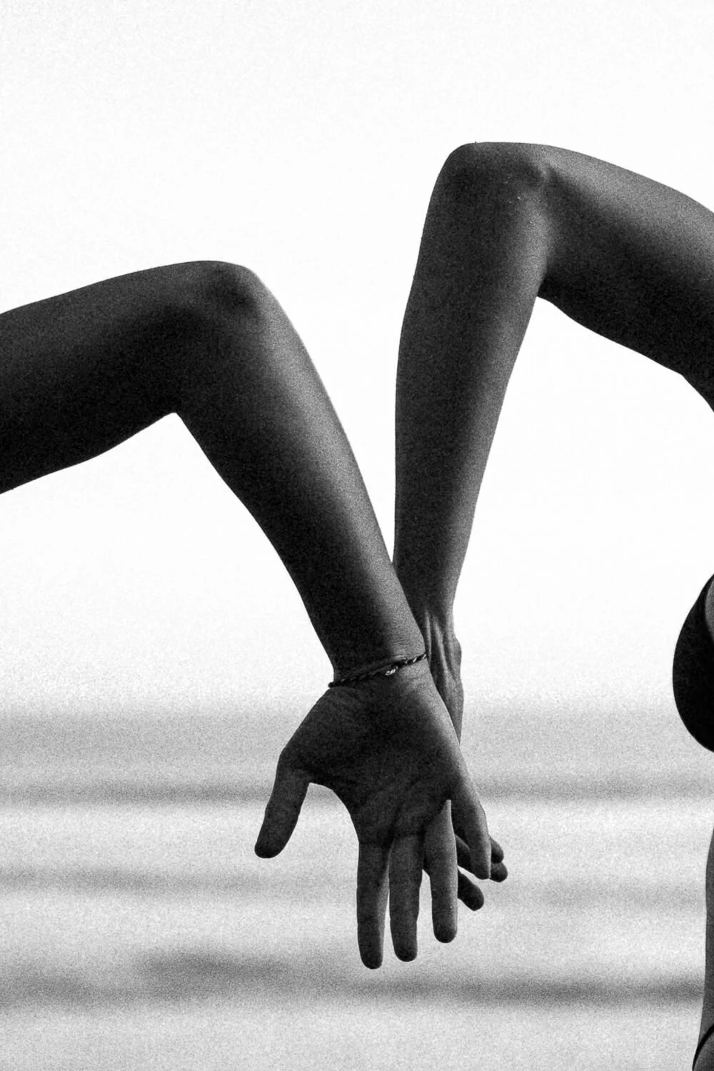 Black and white photo of two hands with fingers intertwined.