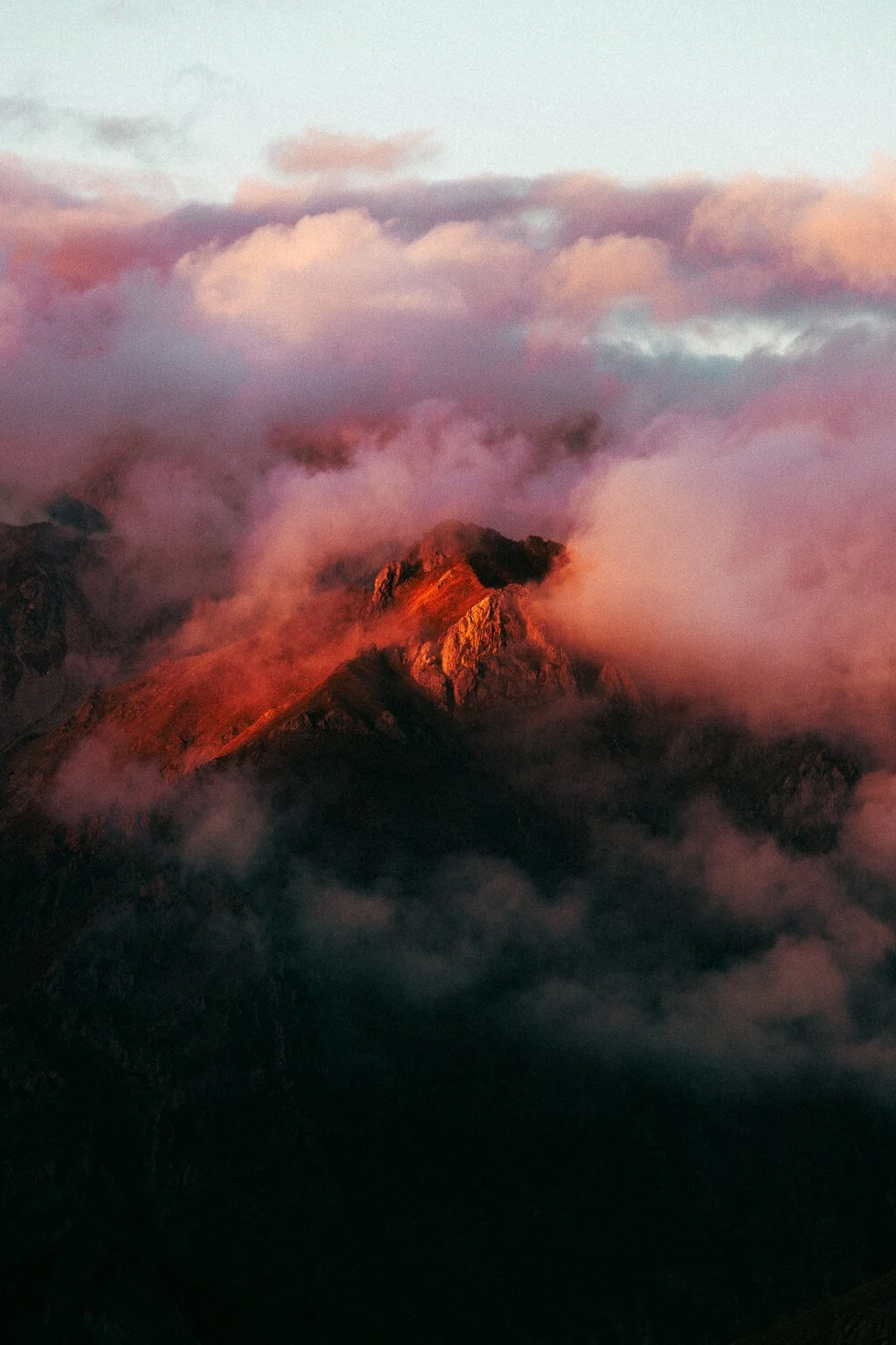 Montagne avec des nuages roses et orange au coucher du soleil.