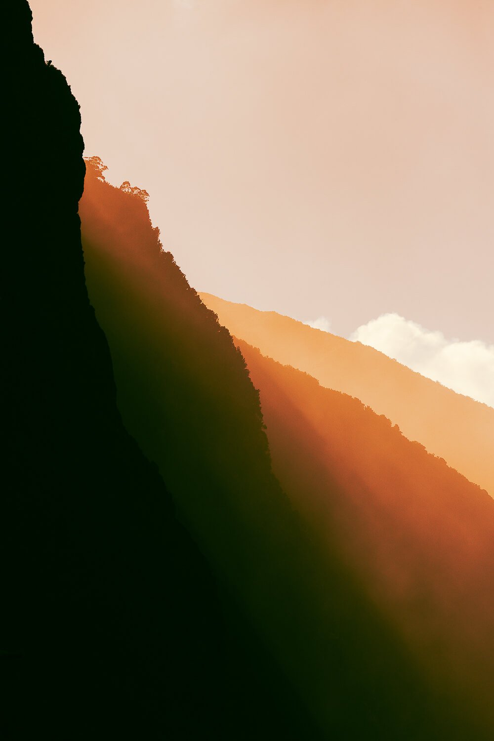 Silhouetted mountain range at sunset with colorful sky and clouds in the background.