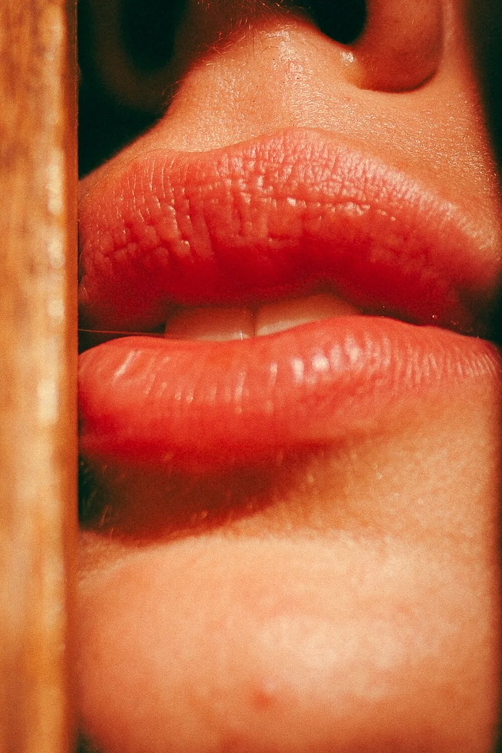 Close-up of a person's lips and part of the nose with a finger partially covering the face.