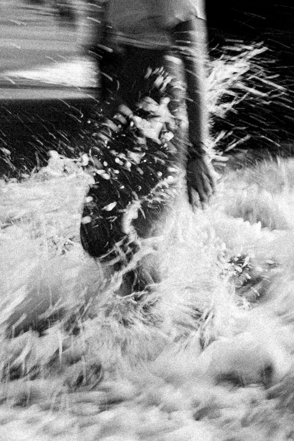 A person in dark clothing walking through a snowstorm, with snow falling heavily and creating a misty scene.