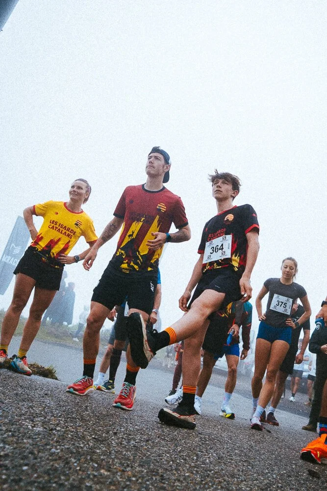 A group of runners in colorful athletic gear, preparing at the starting line, on a foggy day.