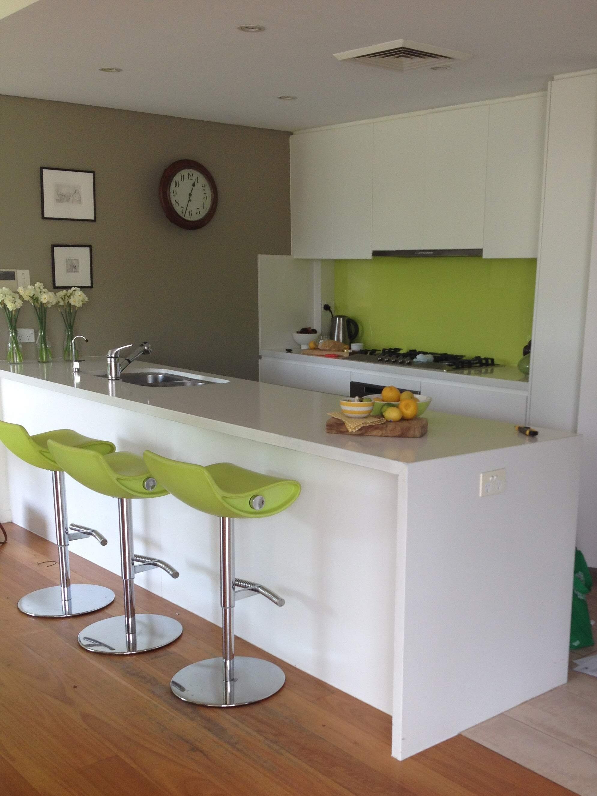 This small new build open plan kitchen was just like all the other kitchens in the development. Clean, white, smart...and a bit dull. We put in a bright green glass splashback and barstools, and painted the end wall to make that part of the room fee