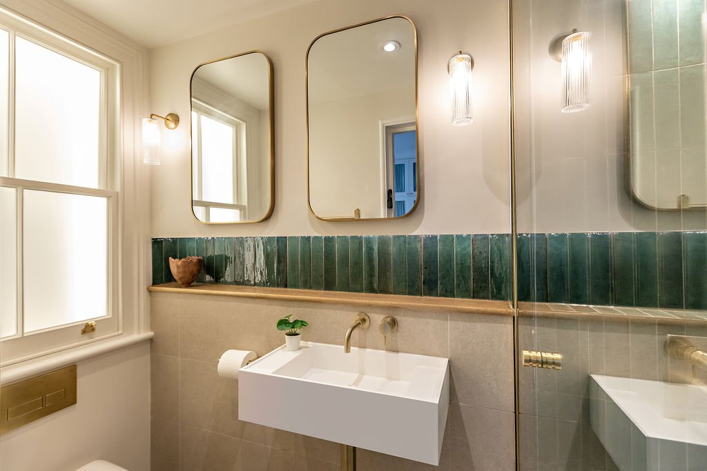a false will with mirrored cabinets - these open for storage. They also allow for a shelf with lighting to sit below them, and behind the basin.