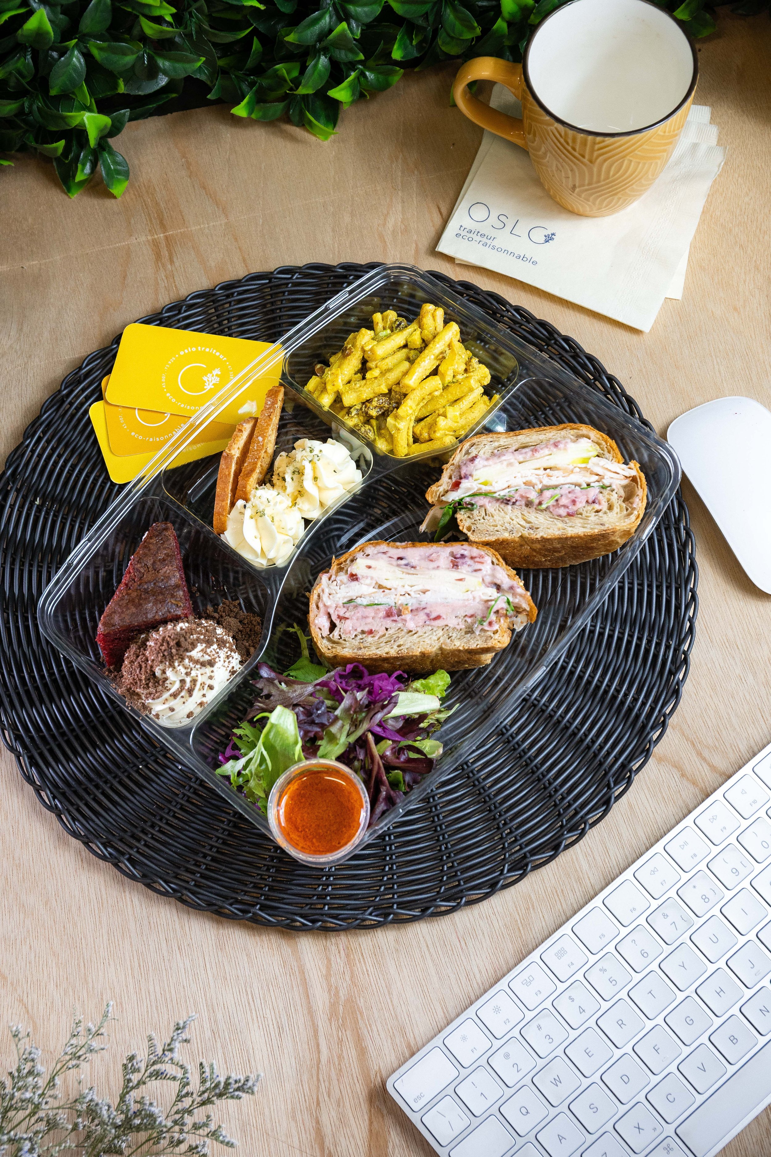 Assiette de plats et desserts avec une sandwich, salade, pâtes, gâteau, sauce et biscuits sur un bureau