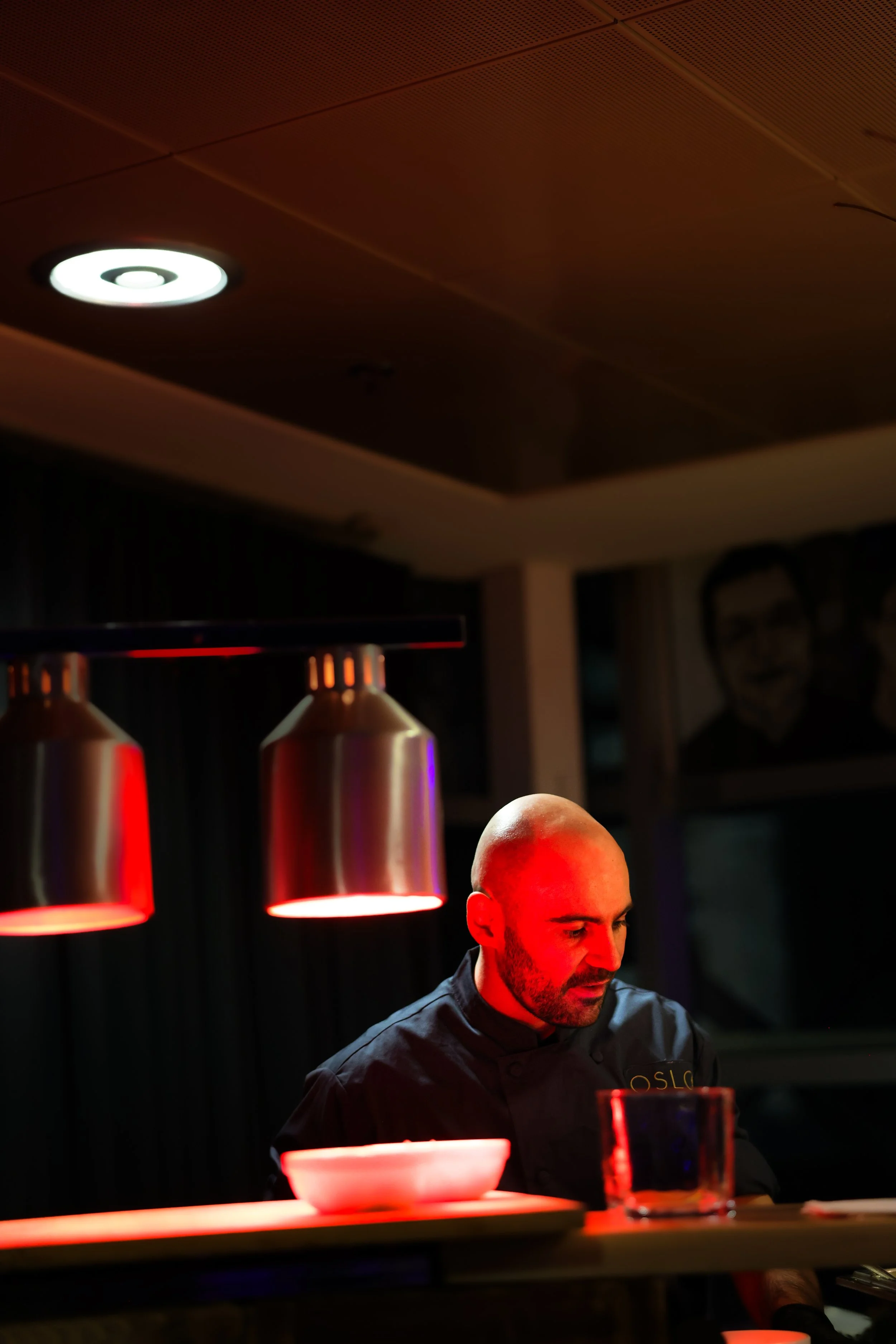 Un homme chauffer professionnel ou chef, en train de travailler dans une cuisine ou un restaurant, sous un éclairage rouge.