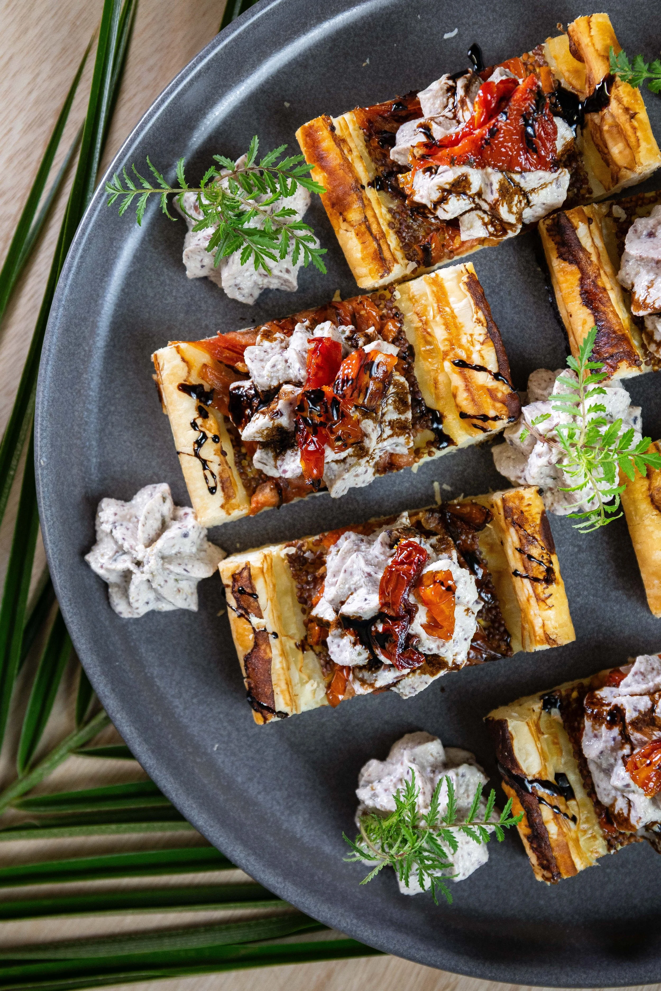 Gâteaux garnis de crème fouettée, de caramel, de chocolat, de morceaux de fruits secs, décorés de feuilles de persil sur une assiette grise.