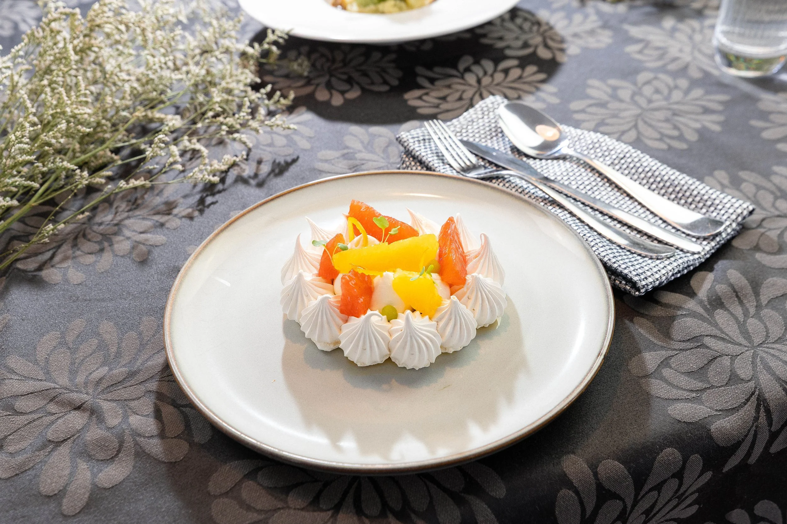 Gâteau de noël dans un plateau présenté sur une table entourée de feuilles vertes et des éléments décoratifs.