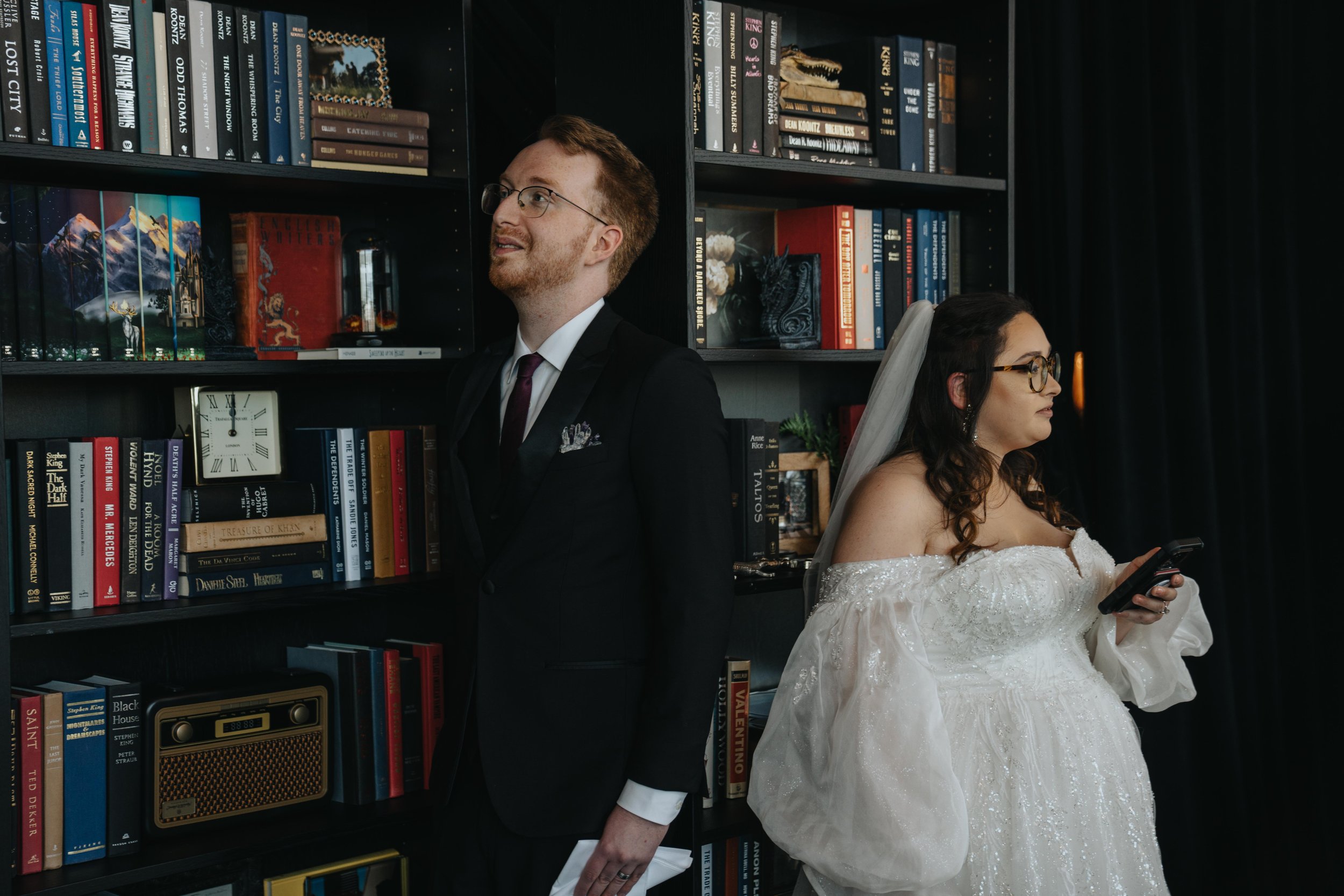 Couple exchanging vows without seeing each other. Moving bookshelves behind then with an assortment of books.