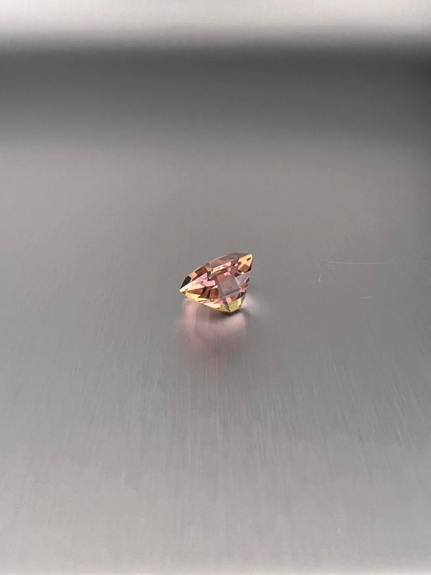 A 2.06 carat bi-color peach tourmaline with a hexagon cut, displaying stunning peach hues and exceptional clarity, highlighting its unique and elegant gem quality.