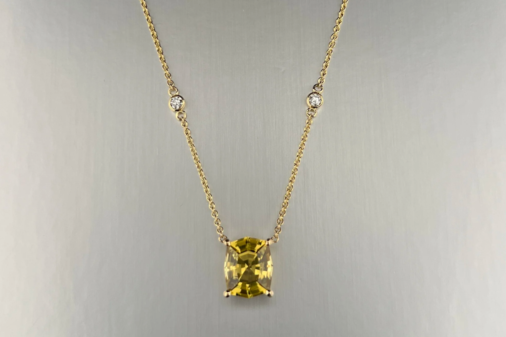 Front view of a custom 18k yellow gold station necklace featuring a 5.01 ct golden zircon with bezel-set natural diamond stations.