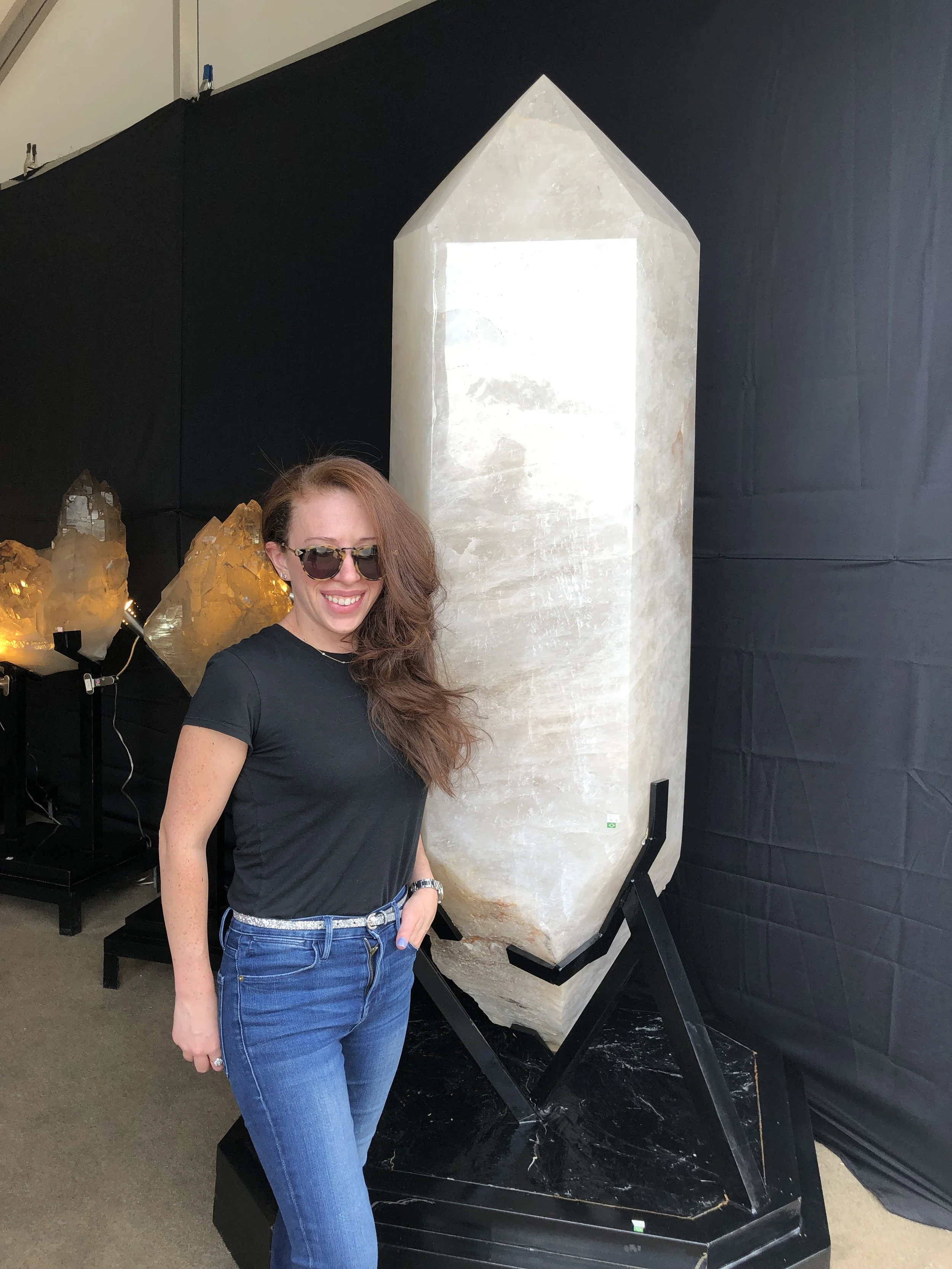 Erica Silverglide standing beside a giant natural quartz crystal during a mineral and gemstone exploration.
